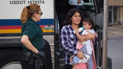 A woman carries a baby as immigrants are dropped off at a bus station shortly after being released from detention through "catch and release" immigration policy in June. AFP