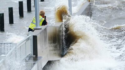 A utility worker photographs waves as they slam against a sea wall in Bay Saint Louis, Mississippi. AP