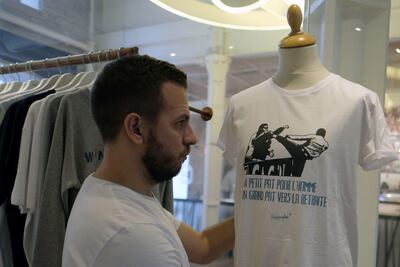 A salesman places a parodic T-shirt reading 'A small step for the man, a giant step towards retirement'. Boris Horvat / AFP