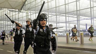 Policemen with batons and shields shout at protesters during a demonstration at the airport in Hong Kong. AP Photo
