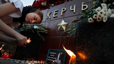 A girl lights a candle in memory of the victims of Wednesday's attack on a vocational college in Kerch, Crimea, at the memorial stone with the word Kerch in the Alexander Garden near the Kremlin, Moscow. AP