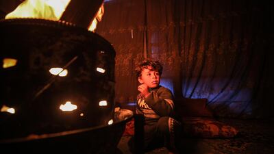 A Palestinian boy sits near a fire in his family's makeshift house during cold weather in the south of Khan Younis Refugee Camp, Gaza Strip. EPA
