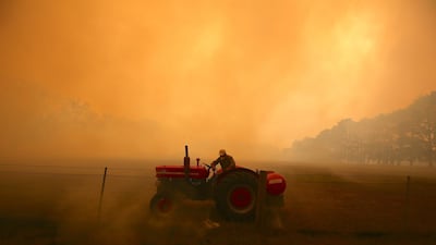 A farmer drives a tractor as he uses a hose to put out a fire burning in his paddock and near homes on the outskirts of the town of Bilpin in Sydney, Australia. Getty Images