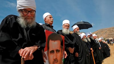 Elderly members of the Druze community stand holding a portrait of Syrian President Bashar Al Assad during a rally in the Druze village of Majdal Shams in the Israeli-annexed Golan Heights. AFP