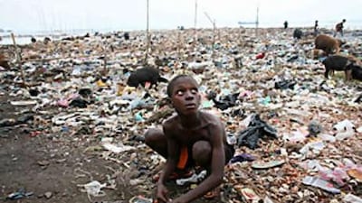 A child plays with his train set surrounded by rubbish in the slums of Freetown in Sierra Leone.