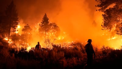 Two firefighters face the Bridge Fire as it blazes in Wrightwood, California. AP