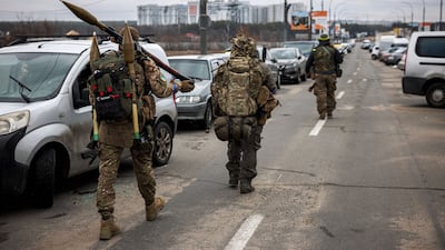 Ukrainian soldiers carry rocket-propelled grenades and sniper rifles as they walk towards the city of Irpin, north-west of Kyiv. AFP