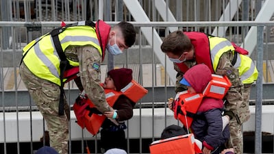 Military personnel help young children in to Dover on May 2, 2022. PA