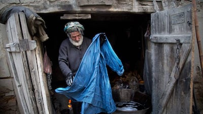 Haji Hussain, 75, who colours clothing for 40 years, takes a freshly colored burqa out for drying in his small shop in the old town of Kabul.