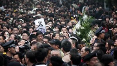 Chinese police officers stand guard while a paper reads, "Don't Cry Shanghai," is seen in the crowds as they gather to watch an apartment building, which were damaged by fire in Shanghai, east China Sunday, Nov. 21, 2010. Thousands of somber Chinese marked a traditional day of mourning Sunday for 58 people killed in the high-rise fire in a gathering closely watched by police. (AP Photo) *** Local Caption *** XAW101_China_Fire.jpg