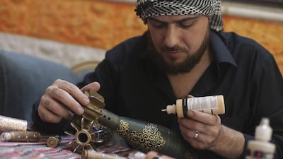 Akram Sweidan decorates on a mortar shell in the Duma neighbourhood of Damascus. Bassam Khabieh / Reuters