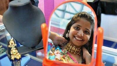 A woman looks in the mirror as she tries on a necklace at a sale of jewellery in India, which is among the leading nations for gold sales. Noah Seelam / AFP