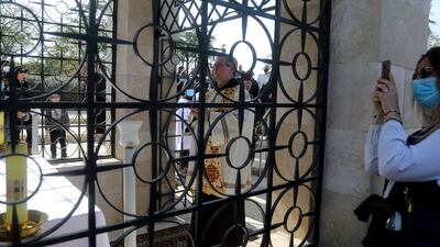 A woman photographs a baptism by the Jordan River.