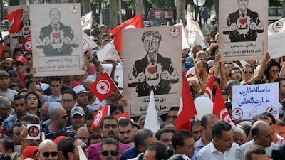 Demonstrators in Tunis hold placards during a march against a bill granting amnesty to officials accused of corruption. Tunisia must create jobs and reduce its government spending in order to get its economy back on track post-Arab Spring. Hassene Dridi / AP