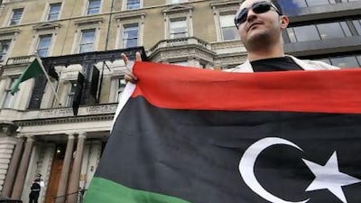 A man holding the flag of the Libyan rebels stands outside the Libyan embassy in London yesterday after Britain recognised the National Transitional Council as the country's sole governmental authority, and expelled diplomats appointed by the Qaddafi regime. Andy Rain / EPA/
