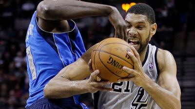 San Antonio Spurs' Tim Duncan (21) is pressured by Dallas Mavericks' Samuel Dalembert (1) during the first half of an NBA basketball game, Sunday, March 2, 2014, in San Antonio. (AP Photo/Eric Gay)