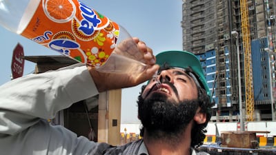 A construction worker gulps down water while working in the heat. The Health Authority - Abu Dhabi launches its Safety in the Heat campaign tomorrow.