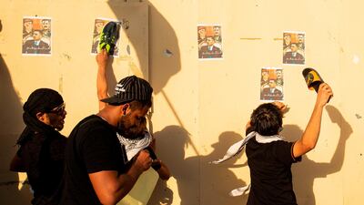 Iraqi youths use their shoes to slap posters of the governor of Basra during a demonstration near his house. AFP