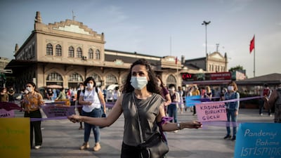 Protesters wearing protective face masks hold placards and shout slogans while maintaining social distance with purple ribbons due to the ongoing coronavirus pandemic during a protest against abuse of women and children in Istanbul, Turkey. EPA