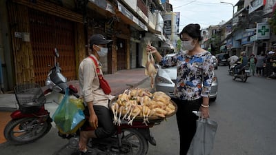 A woman buys a chicken from a street vendor in Phnom Penh. Markets remained closed amid lockdown restrictions introduced in Cambodia to try to halt a surge in cases of Covid-19. AFP