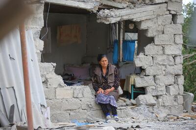 A woman sits in ruins of her house after shelling by Armenian artillery, in Terter, Azerbaijan. AP