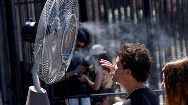A tourist stands in front of a cooling fan installed outside the Colosseum during a heatwave in Rome. Reuters