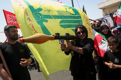 A woman holds a mock grenade launcher next to a Hezbollah flag during a rally in Tehran on August 4. Reuters