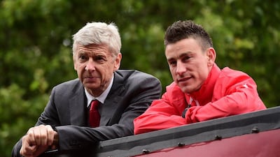 Arsenal's French manager Arsene Wenger, left, and Arsenal's French defender Laurent Koscielny look out from an open top bus during the Arsenal victory parade in London on May 31, 2015, following their win in the English FA Cup final. AFP PHOTO / LEON NEAL