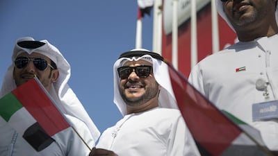 Mohammed Al Obaidli, a senior crisis officer at the Health, Safety and Environment department, joins other employees of the Abu Dhabi Media in raising the UAE national flag. Silvia Razgova / The National