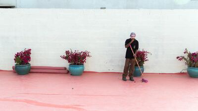 A man sweeps the floor at Al Lokrit Warehouse, the site of Dubai International Flower Festival. Reem Mohammed / The National