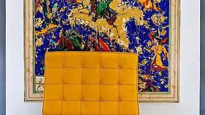 A yellow version of Mies van der Rohe's instantly-recognisable Barcelona chair is set against a dramatic piece of art. Antonie Robertson / The National