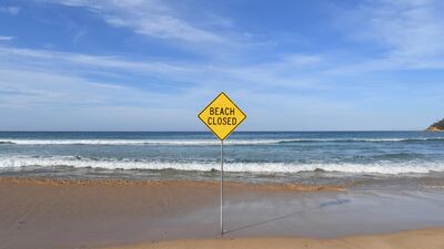 A beach closed sign on Manly Beach in Sydney, Australia. The governments of New South Wales and Victoria are planning to impose lockdowns to fight the spread of coronavirus, with the Australian government pledging a further A$66.4bn to indviduals and small businesses to help reduce the economic impact. Getty Images