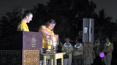 Carolyn Rogers, committee member of Darkness into Light, Abu Dhabi, lights a candle before the walk begins.