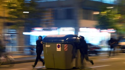 Protesters push a trash container during clashes with Catalan regional police forces. AFP