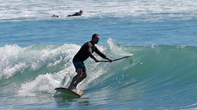 A stand-up paddle boarder surfs across a wave at Sumner Beach in Christchurch, New Zealand. January, 2018 was the hottest month ever recorded in New Zealand, and experts say climate change is one factor. Mark Baker / AP Photo