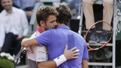 Switzerland's Stanislas Wawrinka, left, embraces countryman Roger Federer at the end of their men's quarter-final match of the French Open in Paris on June 2, 2015. AFP PHOTO / KENZO TRIBOUILLARD