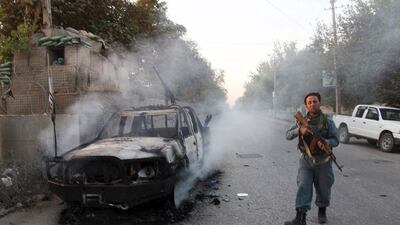 An Afghan policeman patrols next to a burning vehicle in the city of Kunduz on October 1. Reuters