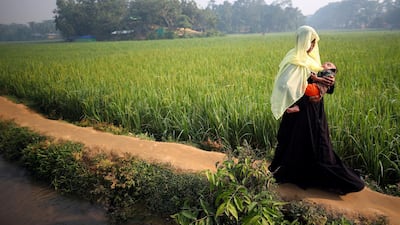 A Rohingya refugee carries her baby through Balukhali refugee camp near Cox's Bazar, Bangladesh. Hannah McKay / Reuters