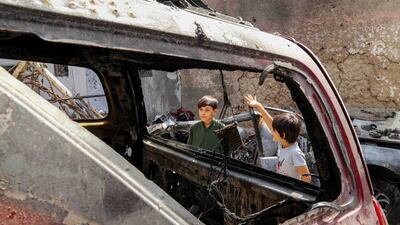 Family members of the victims of a US drone strike stand beside the wreckage a day after the US apologised for mistakenly attacking civilians in Kabul, Afghanistan. EPA