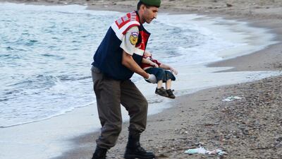 A Turkish gendarme retrieves the body of Syrian refugee Alan Kurdi from a beach in Turkey. Reuters