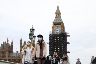 People wearing protective face masks walk over Westminster Bridge in front of the Big Ben, in London, December 15. Reuters