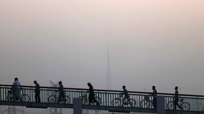 Cyclists cross a bridge in Dubai on a dusty and humid June day. Karim Sahib / AFP