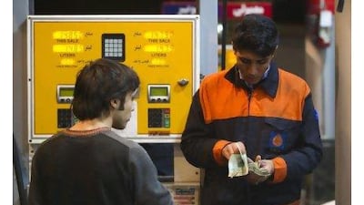 A petrol station attendant counts money as a man waits for his change in northwestern Tehran yesterday.