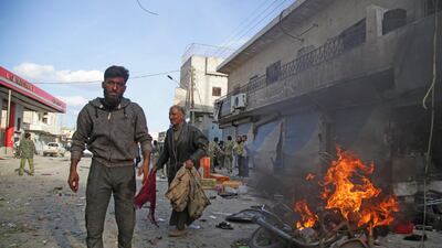 Syrians walk past a burning motorcycle. AFP