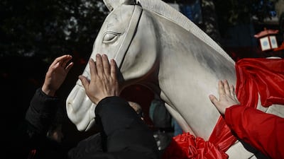 People touch a statue for good luck at a temple in Beijing on the first day of the Year of the Fire Horse. AFP