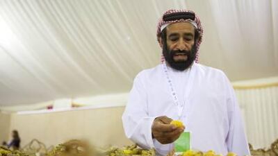 Date judge panel member Faray Rashed Obeid Al Mansouri inspects dates submitted for competition during the Liwa Date Festival.