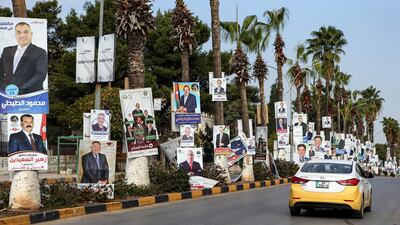 A taxi drives past electoral banners for candidates and lists running in the 2020 general election in Jordan. AFP