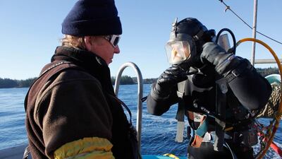 Freddy Gutmann stands by as David Thomas (right) returns on board after harvesting geoduck near Tofino, in British Columbia. Clement Sabourin / AFP