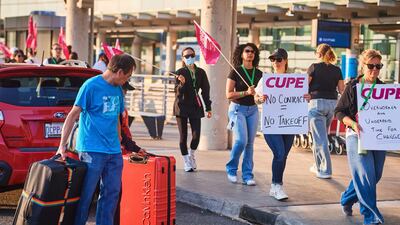 Travellers pass Air Canada flight attendants on strike at Pearson International Airport in Toronto on Saturday. The Canadian Press via AP