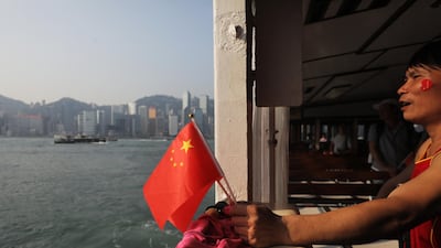 A pro-government supporter holds Chinese flags while crossing Victoria Harbour in Hong Kong. Bloomberg
